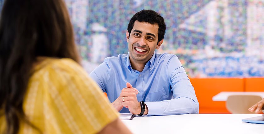 Man In Blue Shirt Smling At Person Opposite Him